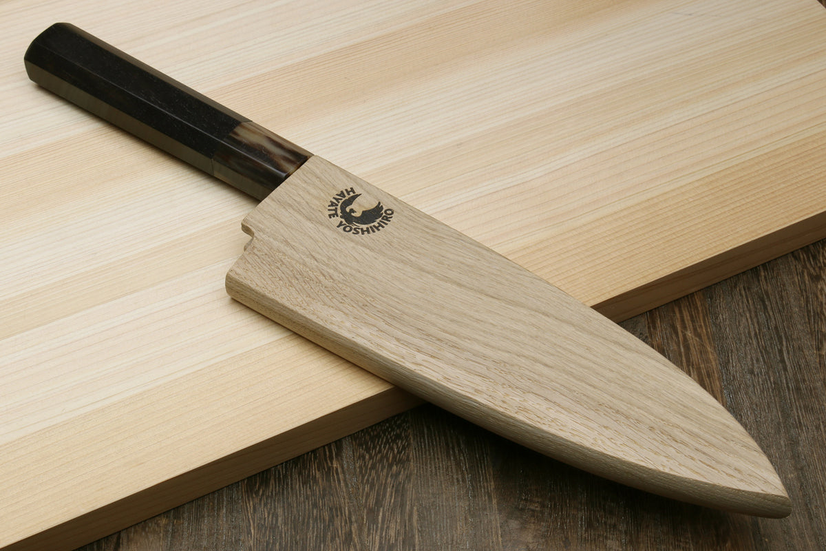Deba chef knife on wooden board with white blade and ebony-style dark handle