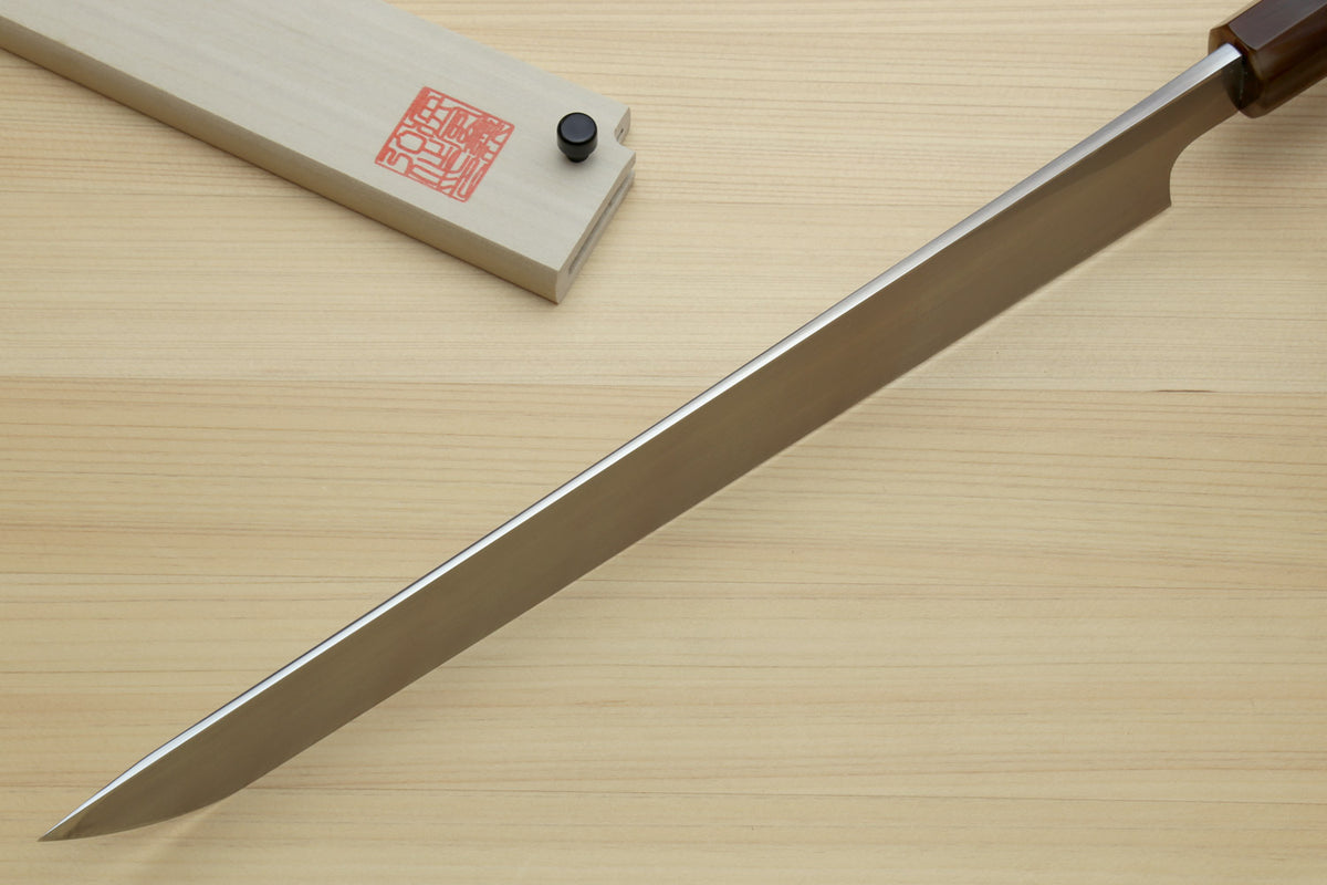 Sashimi sushi knife with long pointed white steel blade and dark handle on wood