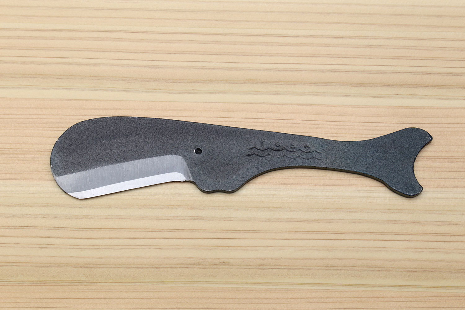 Utility knife with dark kurouchi finish, whale pattern, and curved silver blade