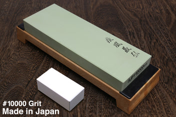10000-grit sharpening whetstone on wooden base, pale green stone with dark label edge