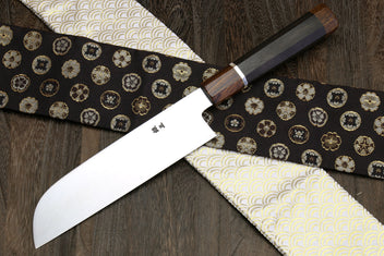 Japanese chef knife close-up with mirror-polished blade and dark wooden handle