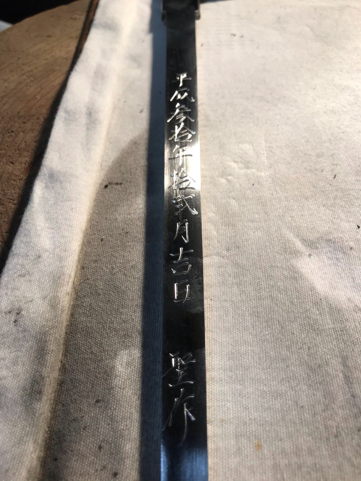 Single-edged tuna knife blade closeup with etched Japanese characters
