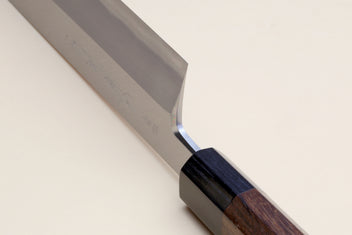 Traditional Japanese vegetable knife with blue steel blade and rosewood handle, angled close-up