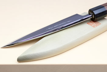 Deba knife edge and blade close-up with white steel and rosewood handle, dark bolster