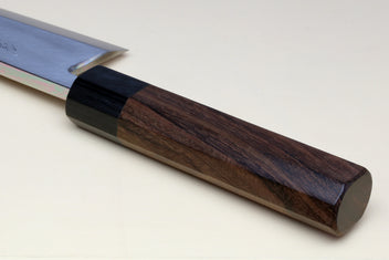 Deba knife handle close-up: dark bolster and brown rosewood scales on a white blade
