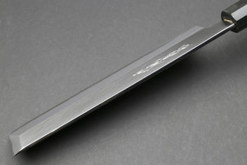 Japanese chef knife blade close-up with polished edge and dark bolster