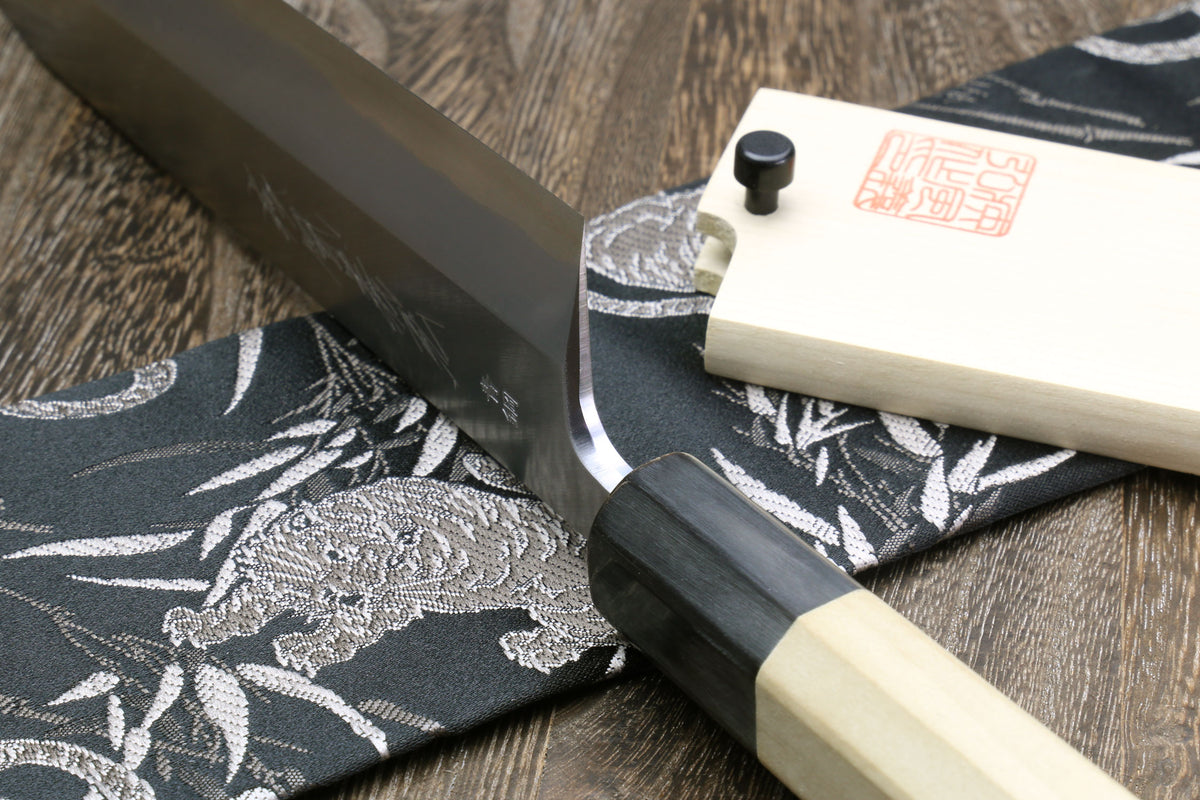 Eel filet knife handle detail with dark collar and pale saya on patterned cloth