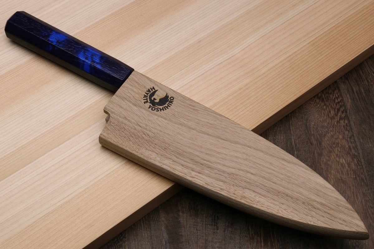 Japanese deba knife resting on wood with dark blue handle and stainless blade