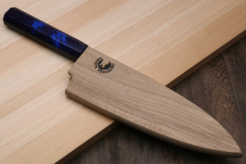 Japanese deba knife resting on wood with dark blue handle and stainless blade