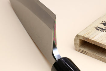 Deba knife close-up of dark rosewood handle and white steel blade at the spine