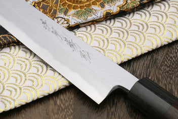 Yanagi knife blade close-up on white steel with engraved markings