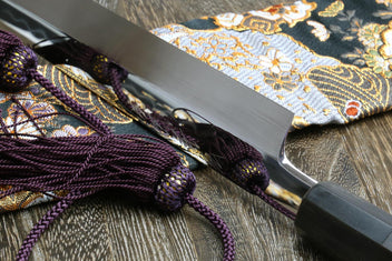 Yanagi knife blade close-up, mirror-finished white steel with decorative etching