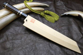 Japanese-style kitchen knife with wavy steel blade and light wood sheath, green cord tassel