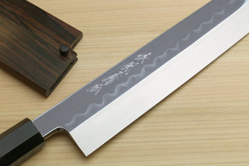 Japanese kitchen knife blade close-up with wavy hamon and etched text