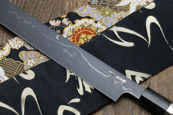 Mirror-finished Japanese kitchen knife with dark handle and silver-toned bolster
