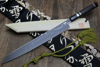 Japanese kiritsuke-style knife with mirror-finished blade, dark handle, and cloth wrap