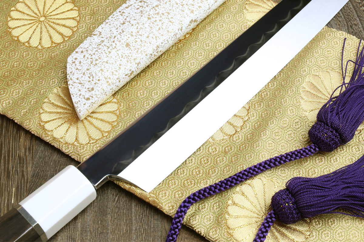 Japanese sushi sashimi knife showing black blade and white handle cap with purple tassel