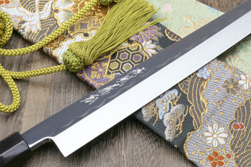 Japanese kitchen knife, mirror blade edge detail and black sheath with green cords