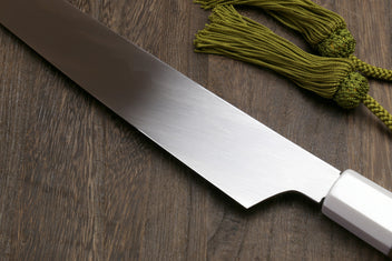 Japanese sushi knife blade with curved profile and white steel finish, dark handle