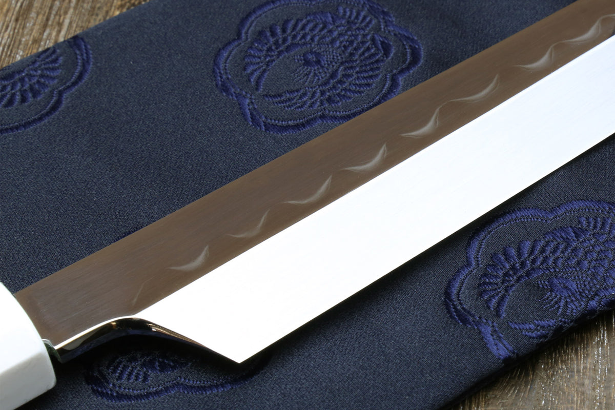 Japanese sushi knife with white steel blade and dark handle on fabric pouch