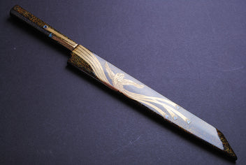Yanagi kiritsuke knife angled view with ornate gold-and-silver pattern on mirror blade