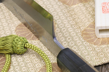 Japanese chef knife close-up: dark ebony handle and gray blade edge