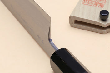 Japanese vegetable knife with curved blade near heel and black handle; wooden saya shown