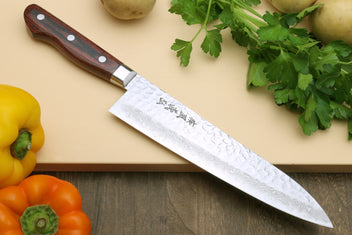 Damascus kitchen knife with dark wood handle and textured patterned blade
