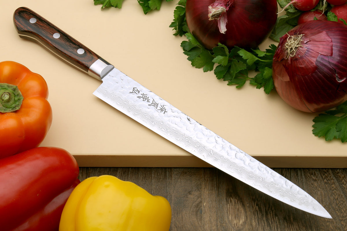 Damascus kitchen knife with dark wood handle on cutting board