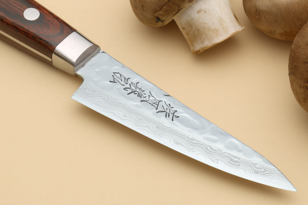 Damascus paring knife blade with etched markings and dark wood handle