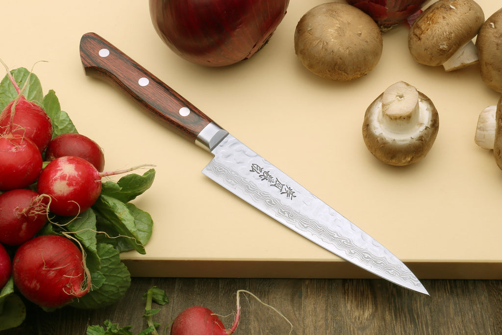 Damascus-pattern knife with dark wood handle with vegetables and herbs