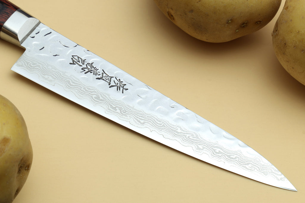 Damascus-pattern santoku blade with engraved markings and pointed tip