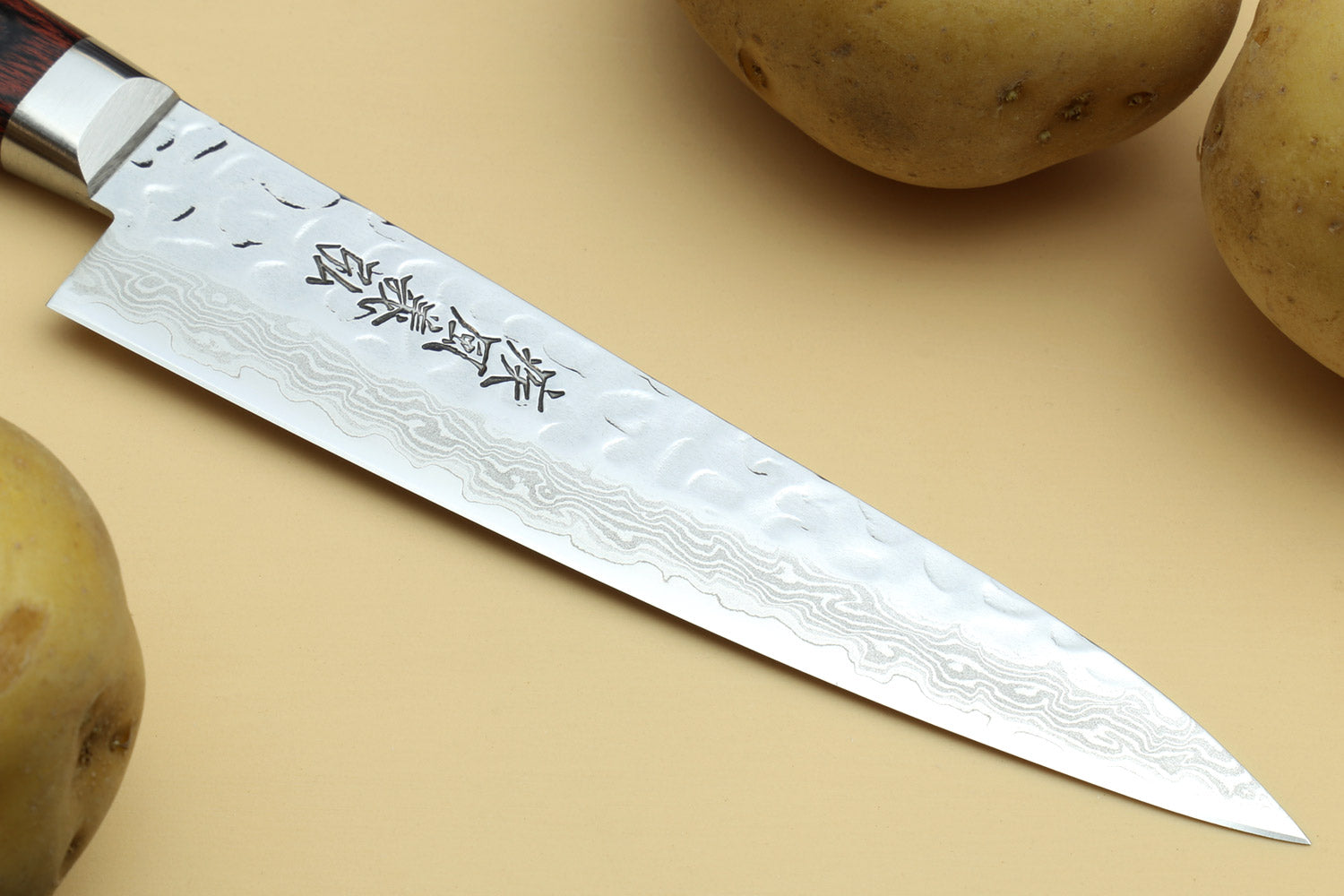 Damascus-pattern santoku blade with engraved markings and pointed tip